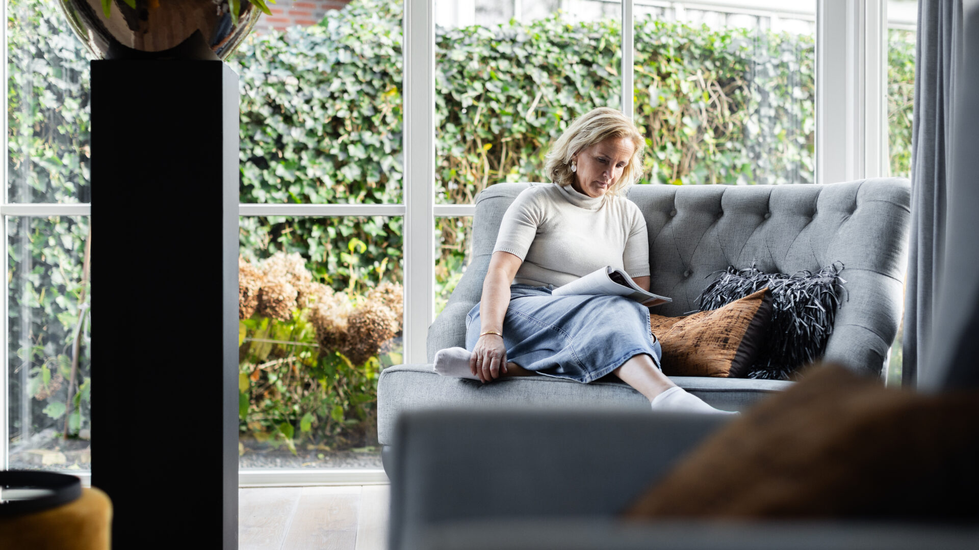 Annelies leest in een rustige, lichte zithoek – moment van reflectie, aandacht en persoonlijke groei.