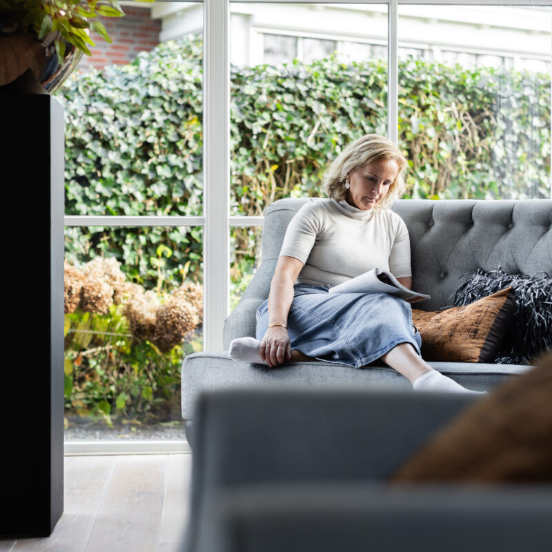 Annelies leest in een rustige, lichte zithoek – moment van reflectie, aandacht en persoonlijke groei.