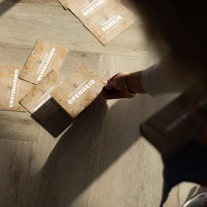 Kaarten met kernwaarden zoals openheid, kwetsbaarheid en eerlijkheid op de vloer tijdens een sessiewerkvorm.