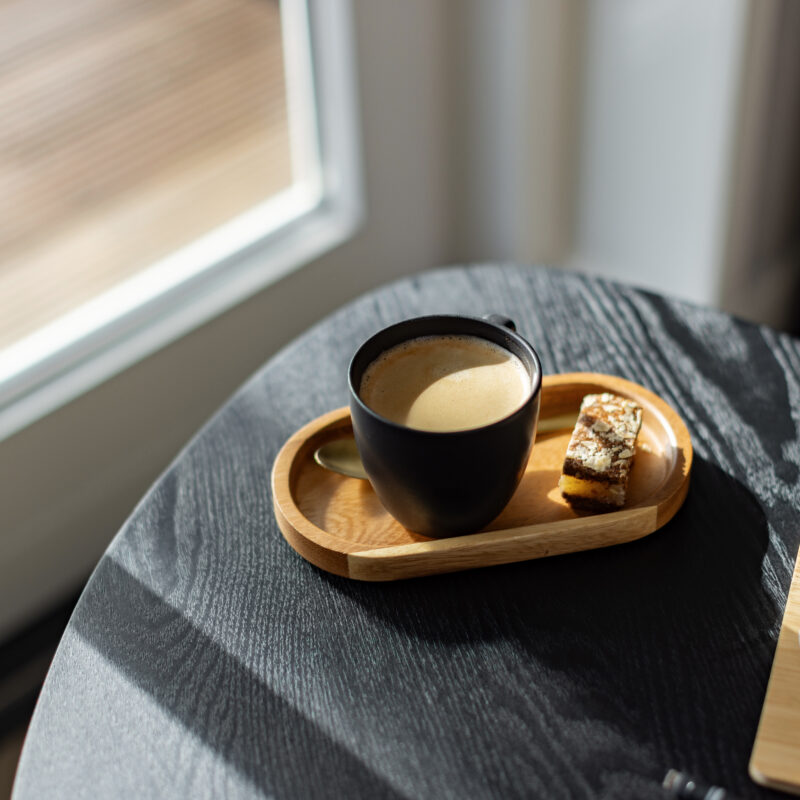 Kop koffie met lekkernij op een bijzettafel in een lichte coachingruimte.