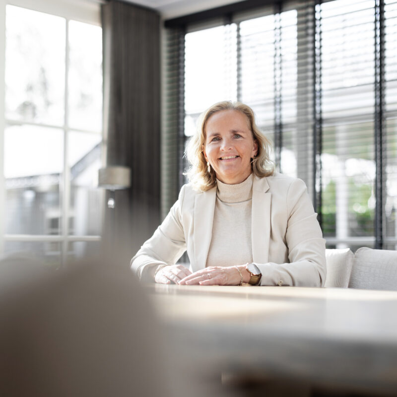 Annelies in een lichte ruimte, warm en open aan tafel.